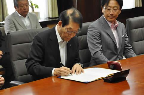 京都産業大学　大城　光正　学長が協定書に署名の写真