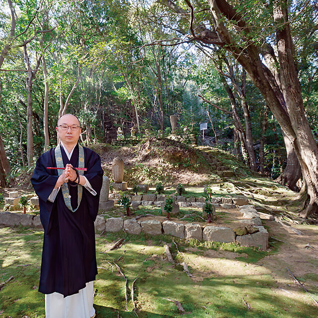 墓の前で合掌する髙木智英住職