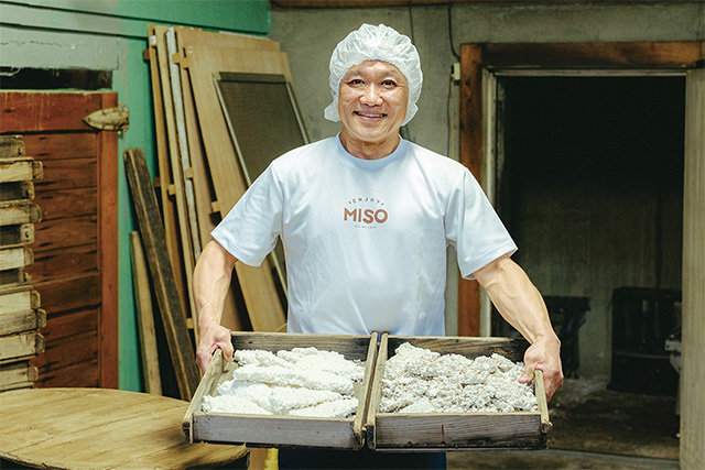 原材料となる麦麹 作業場で発酵した麹を持つ久保さん