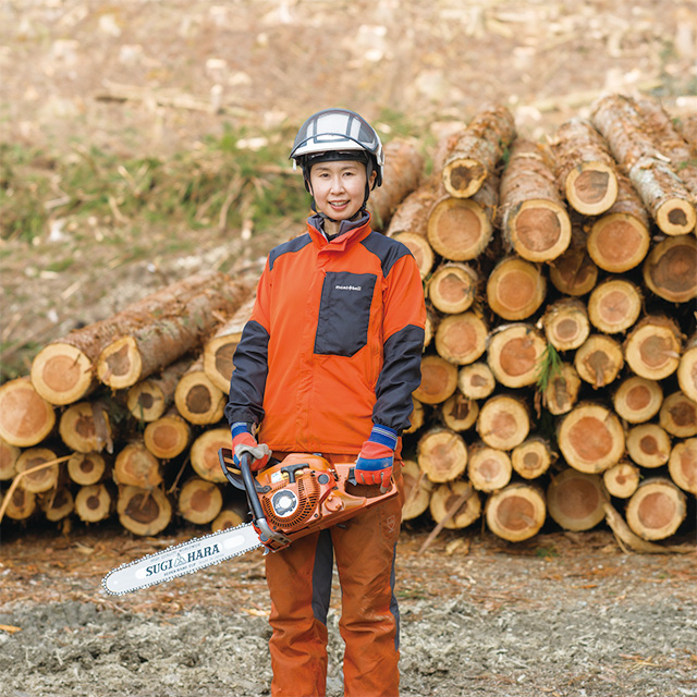 チェーンソーを持ち材木の前に立つ辻𦚰奈津実さん