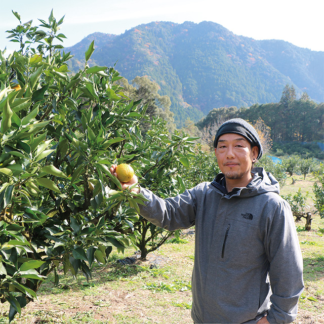 木に実るじゃばらを手にする宇城公揮さん