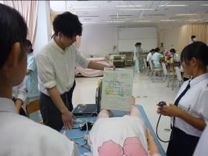 呼吸音聴取体験で参加者に聴診器を当てる場所を説明する看護学生