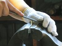 金属を手と工具を使って加工しているところ